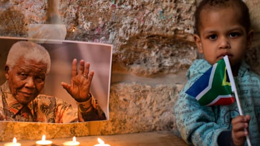 A Jérusalem, un enfant tient un drapeau sud-africain à côté d'un petit autel en hommage à Mandela.