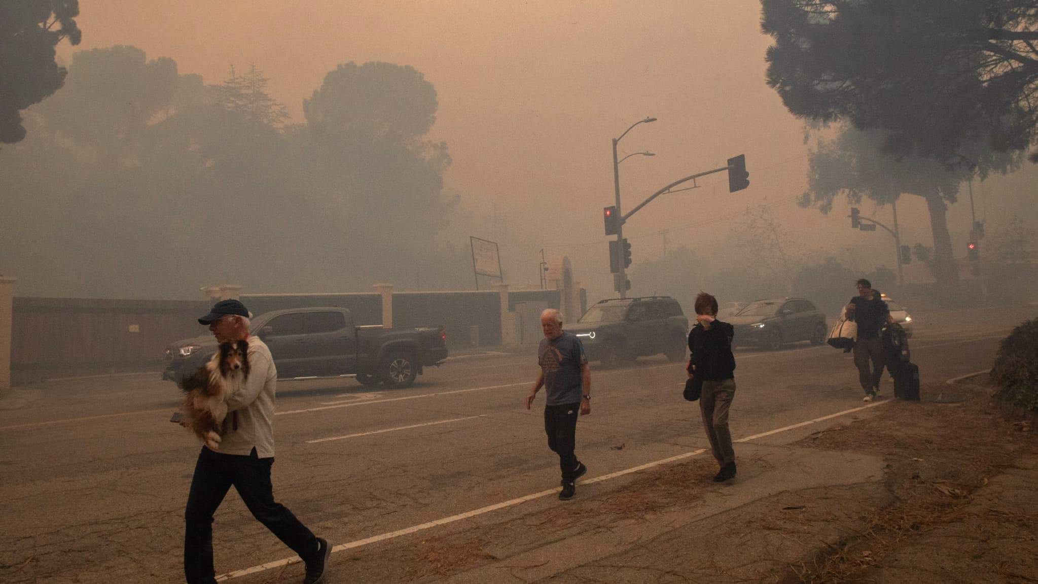 Des personnes évacuent le long de Sunset Boulevard alors que l'incendie de Palisades brûle au milieu d'une puissante tempête de vent, le 7 janvier 2025, à Los Angeles, en Californie. 