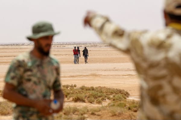 Des gardes-frontières libyens et des migrants, près d'Al-Assah, à la frontière entre la Libye et la Tunisie, le 30 juillet 2023.