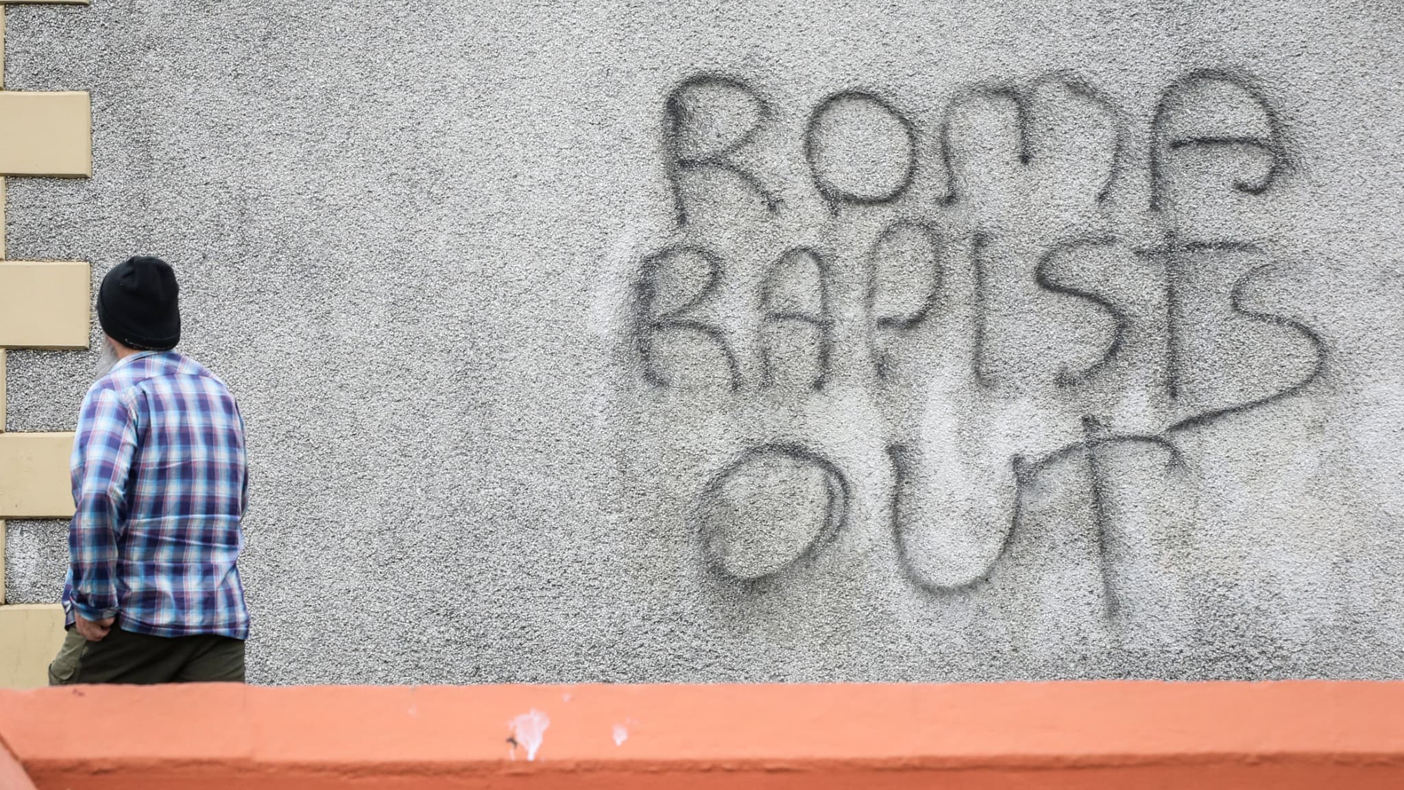 Un piéton passe devant un graffiti portant l'inscription "Roma rapists out" ("Les violeurs roms dehors") après une deuxième nuit de manifestation anti-immigration à Ballymena, en Irlande du Nord, le 11 juin 2025.