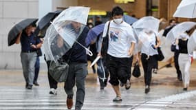 Des piétons devant la gare d'Osaka, au Japon, durant la tempête tropicale Lan, le 15 août 2023.