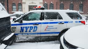 Un véhicule de la police de New York recouvert de neige est visible au milieu d'une tempête hivernale le 25 janvier 2026 dans le quartier de Flatbush, dans l'arrondissement de Brooklyn, à New York.