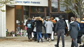 Adultes et enfants viennent déposer des fleurs devant l'école de Conflans-Sainte-Honorine, le 17 octobre 2020 au lendemain de la décapitation d'un des professeurs