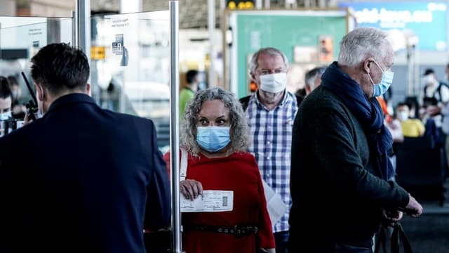 Des passagers, le visage couvert d'un masque pour se protéger du coronavirus, font la queue pour embarquer à l'aéroport de Bruxelles-Zaventem lors de sa réouverture, le 15 juin 2020