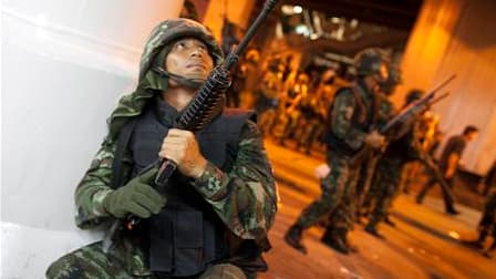 Militaires thaïlandais dans les rues de Bangkok. Les policiers se sont postés devant une barricade érigée par les manifestants antigouvernementaux dans le quartier des affaires de Silom, où trois personnes ont trouvé la mort jeudi soir dans des tirs de gr