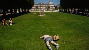 Des gens prennent un bain de soleil au Jardin du Luxembourg, à Paris, le 30 juin 2025, alors qu'une vague de chaleur frappe l'Europe.