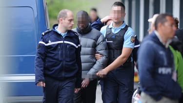 L'un des accusés des meurtres de Kevin et Sofiane sort du tribunal, escorté par la police.