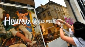 Une commerçante installe un message de bienvenue pour la clientèle, le 11 mai 2020 dans une boutique à Bordeaux
