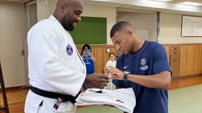 Kylian Mbappé signe un autographe sur un kimono tendu par Teddy Riner, ce jeudi 22 juillet 2022 à Tokyo
