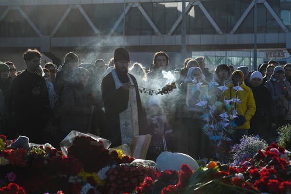 Un prêtre orthodoxe dirige une messe devant le Crocus City Hall en hommage aux victimes de l'attentat près de Moscou, le 25 mars 2024