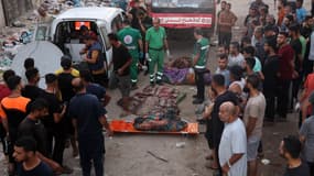 Des Palestiniens déplacés observent des secouristes qui se préparent à transporter les corps des personnes tuées lors d'une frappe israélienne sur une école de la ville de Gaza le 10 août 2024.