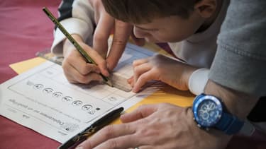 Un père et son enfant font l'école à la maison le 17 mars 2020 à Mulhouse, dans le Haut-Rhin (photo d'illustration)
