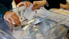 Une personne glissant un bulletin de vote dans une urne (Photo d'illustration).