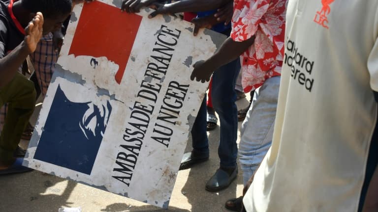 Des manifestants tiennent un panneau de l'ambassade de France après un rassemblement en soutien aux militaires putschistes au Niger, le 30 juillet 2023 à Niamey