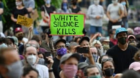 Des manifestants blancs, l'un armé d'une pancarte disant "le silence blanc tue", lors d'une manifestation à Brooklyn le 5 juin 2020