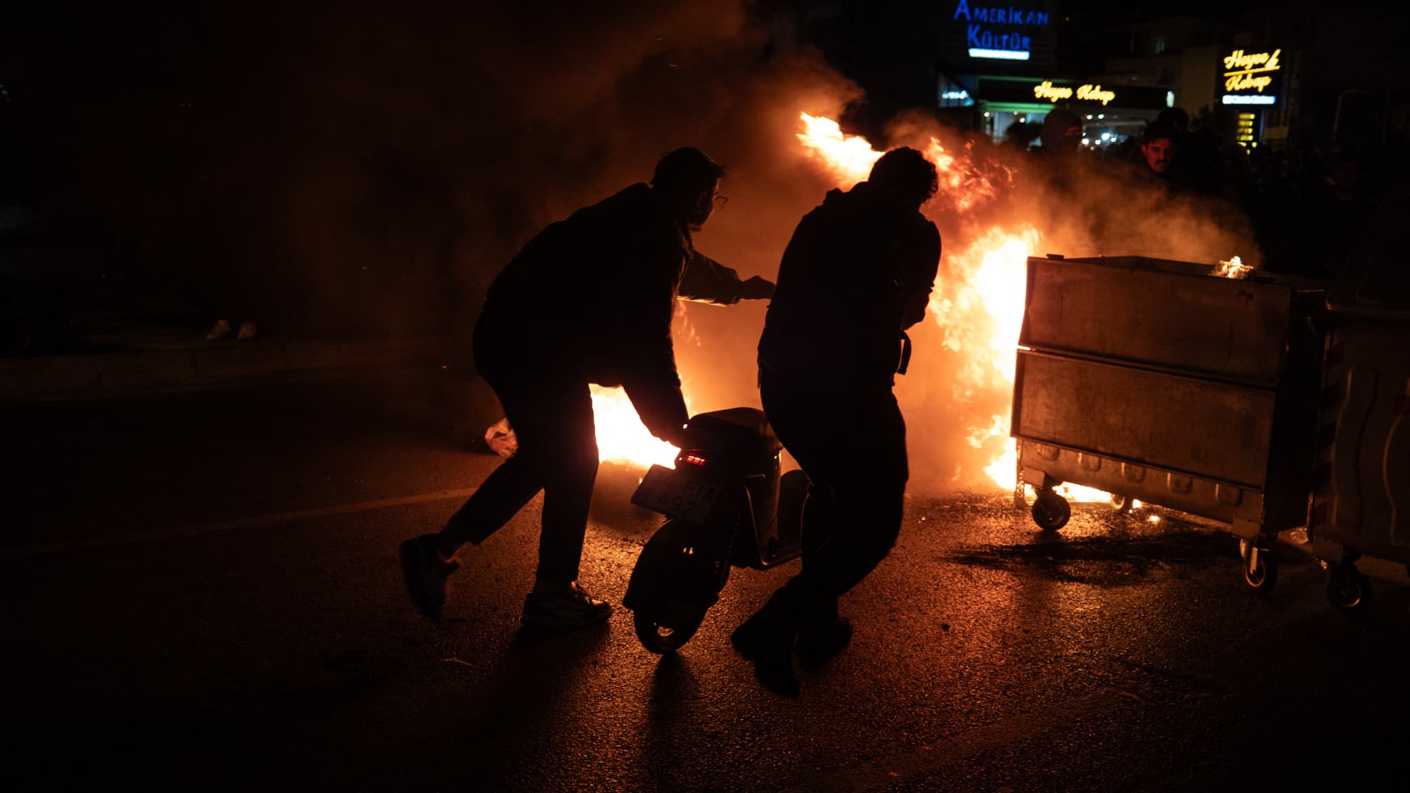 Des manifestants poussent un scooter dans un barrage de feu lors d'une manifestation suite à l'arrestation du maire d'Istanbul, à Izmir (Turquie), le 21 mars 2025.