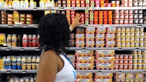 Une femme au rayon yaourts d'un supermarché. 