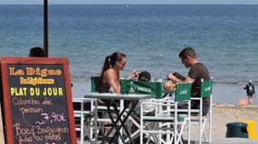 Une famille déjeune le 30 juillet 2008 à la terrasse d'un restaurant le long de la plage de Saint-Aubin-sur-Mer.