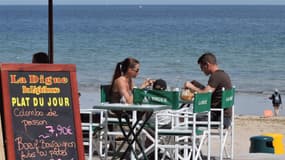 Une famille déjeune le 30 juillet 2008 à la terrasse d'un restaurant le long de la plage de Saint-Aubin-sur-Mer.