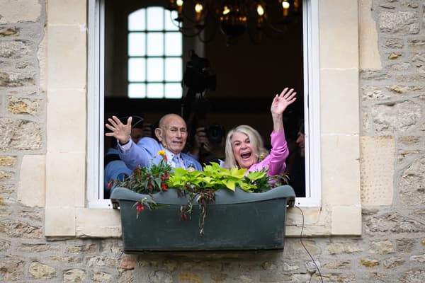 Jeanne Swerlin et Harold Terens saluent la foule depuis une fenêtre alors qu'ils célèbrent leur mariage à la mairie de Carentan-les-Marais.