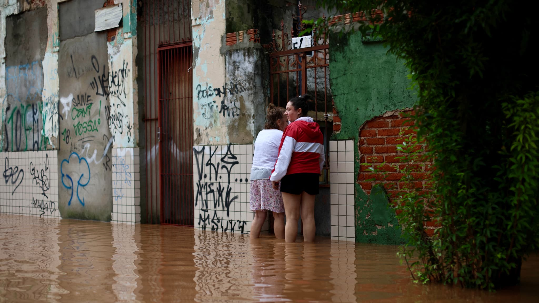 Des habitants du quartier de São Geraldo se tiennent devant leur maison dans une rue inondée à Porto Alegre, dans l'État du Rio Grande do Sul, au Brésil, le 4 mai 2024.