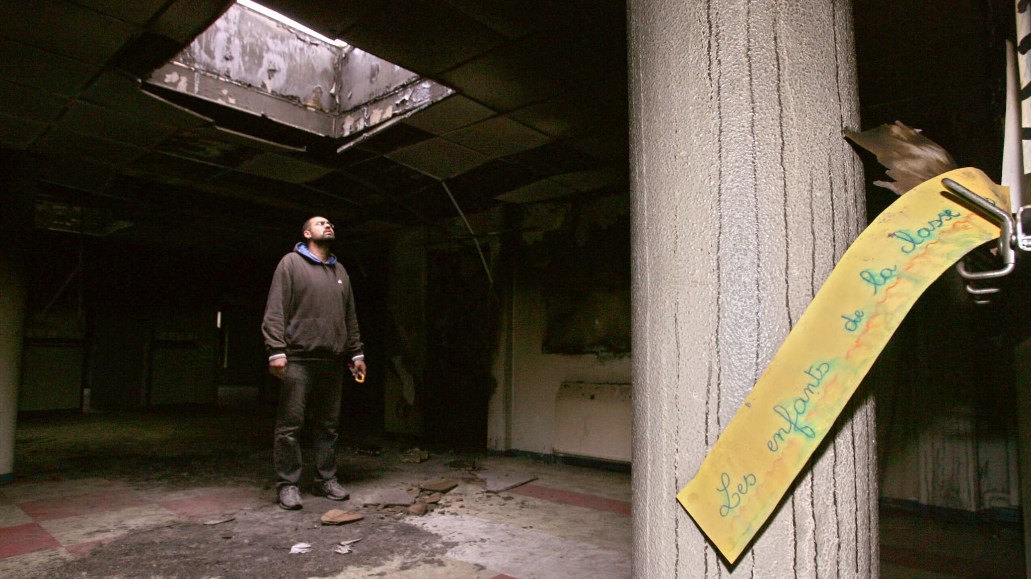 Un électricien inspecte les dégâts le 7 novembre 2005 dans une école incendiée à Grigny (Essonne) lors d'émeutes nocturnes/ 