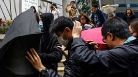 Des militants couvrent leurs visages avec des parapluies en quittant le tribunal de Hong Kong, le 17 mars 2017