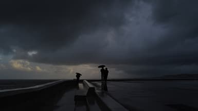 Des personnes se tiennent sous des parapluies pendant une forte pluie à Nice sur la Côte d'Azur, le 3 mars 2024.