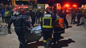 Les secours transportent le corps d'une victime lors d'une opération de sauvetage après l'effondrement de deux immeubles dans le quartier Al Massira de Fès, tard dans la soirée du 9 décembre 2025.