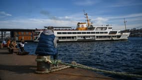 Un ferry est amarré au port de Karakoy à Istanbul alors que des gens sont assis sur la rive du Bosphore, le 8 février 2021 à Istanbul. (illustration)
