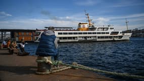 Un ferry est amarré au port de Karakoy à Istanbul alors que des gens sont assis sur la rive du Bosphore, le 8 février 2021 à Istanbul. (illustration)
