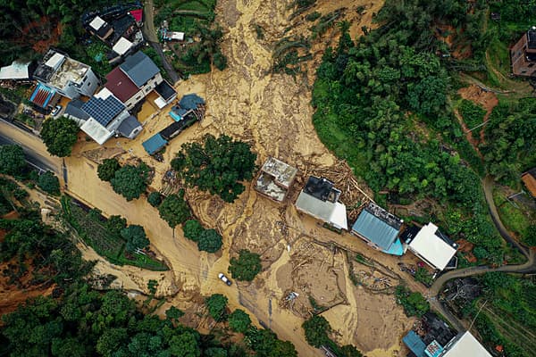 Cette photo montre une vue aérienne d'une voiture passant à côté d'un site de glissement de terrain après des tempêtes à Longyan, dans la province de Fujian, dans l'est de la Chine, le 17 juin 2024.