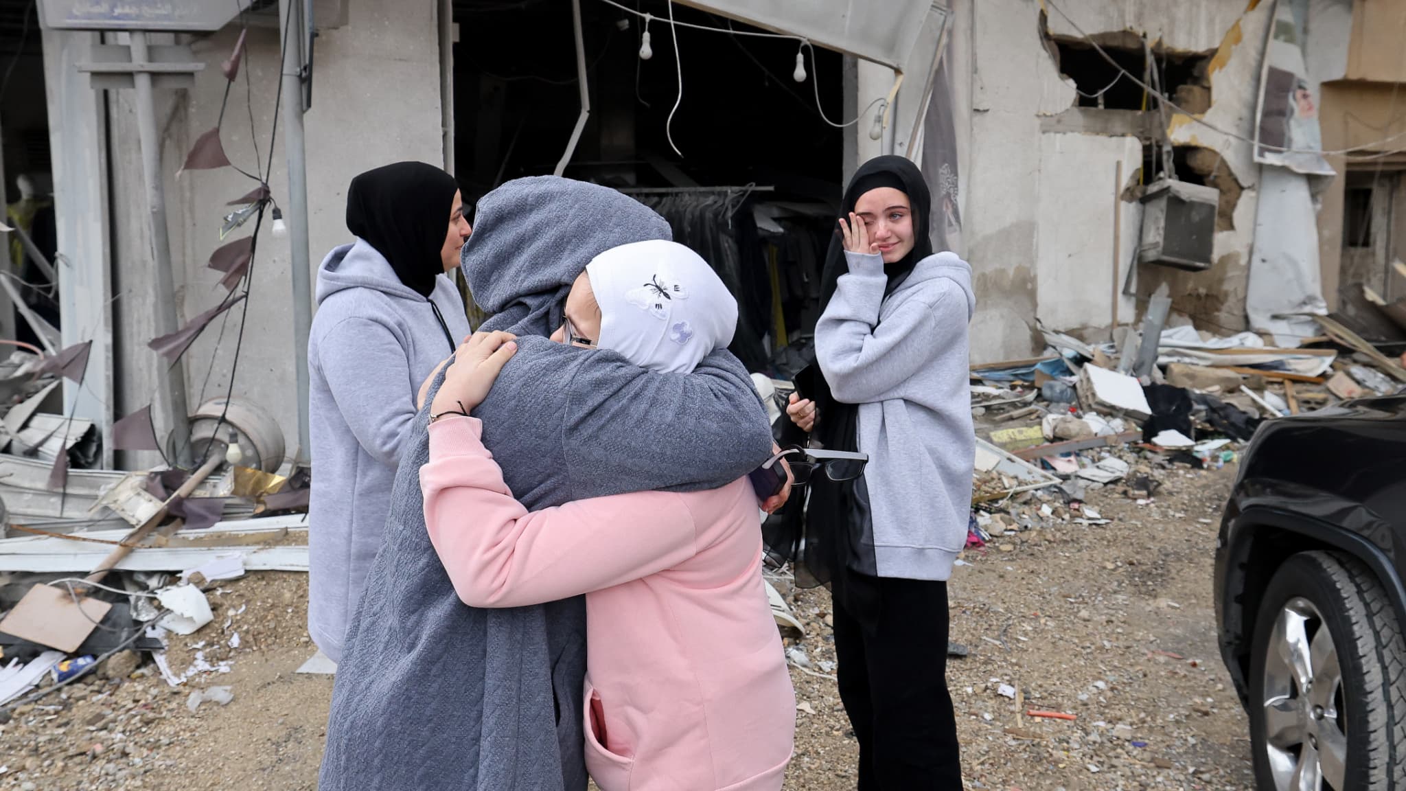 Des femmes s'étreignent face à l'ampleur des dégâts sur leurs foyers, le 27 novembre 2024, dans la ville méridionale de Qana dans le sud du Liban. 