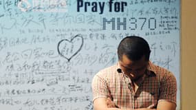 Un homme se tient devant un panneau en soutien aux familles de l'avion disparu de la Malaysia Airlines, à Pékin.