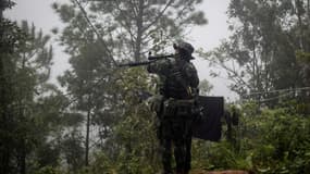 Un rebelle anti-junte pointe son arme pendant un entraînement dans une forêt de l'Etat Karen, en Birmanie, le 16 octobre 2021