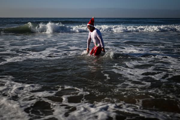 Un homme portant un chapeau de Père Noël prend son premier bain de l'année lors des célébrations du Nouvel An sur la plage de Carcavelos à Oeiras, dans la banlieue de Lisbonne, le 1er janvier 2024.