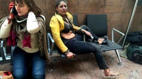 Une voyageuse gît sur les sièges du hall de l'aéroport, hébétée, après l'explosioon terroriste qui a touché l'aéroport de Bruxelles.