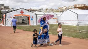 Une femme quitte un hôpital de campagne avec ses enfants dans la ville de Mamoudzou, sur le territoire français de Mayotte dans l'océan Indien, le 24 décembre 2024, une semaine après le passage du cyclone Chido sur l'archipel.
