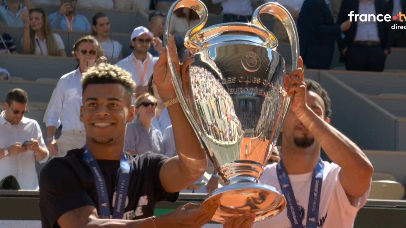 Les joueurs du PSG Désiré Doué et Warren Zaïre-Emery montrent la Ligue des champions au public de Roland-Garros le 1er juin 2026 Les joueurs du PSG Désiré Doué et Warren Zaïre-Emery montrent la Ligue des champions au public de Roland-Garros le 1er juin 2026