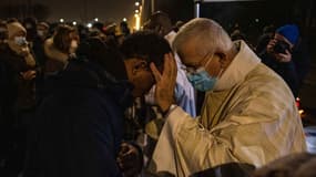 L'évêque d'Arras, Mgr Olivier Leborgne, bénit une personne au cours d'une messe organisée près d'un campement de migrants à Calais, le 24 décembre 2021.