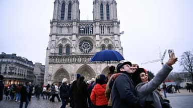 Des personnes prennent un selfie devant Notre-Dame de Paris, le 24 décembre 2024