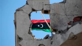 Un drapeau du royaume de Libye, symbole de l'insurrection, à Syrte. Le Conseil national de transition annoncera finalement dimanche à Benghazi la libération du pays. /Photo prise le 21 octobre 2011/REUTERS/Thaier al-Sudani