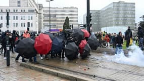 Des manifestants s'abritent derrière des parapluies durant des heurts avec la police en marge d'une manifestation contre la réforme des retraites à Nantes, le 11 mars 2023
