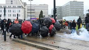 Des manifestants s'abritent derrière des parapluies durant des heurts avec la police en marge d'une manifestation contre la réforme des retraites à Nantes, le 11 mars 2023