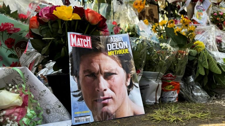 Un portait d'Alain Delon en Une du magazine Paris Match déposé parmi les fleurs devant la propriété de l'acteur décédé, le 21 août 2024 à Douchy, dans le Loirete 
