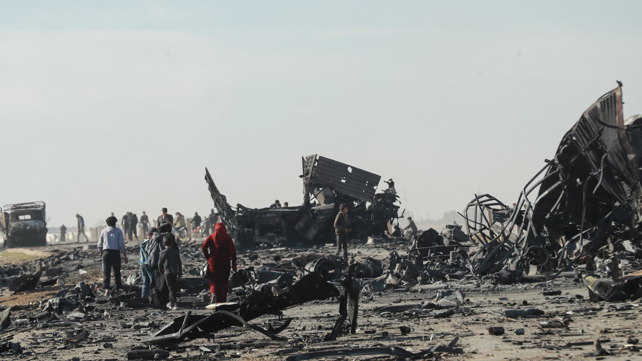 Des personnes ramassent du métal et des munitions non explosées sur le site de la frappe aérienne israélienne de la veille qui a visé des cargaisons d'armes appartenant aux forces gouvernementales syriennes à Qamishli, dans le nord-est de la Syrie, principalement kurde, le 10 décembre 2024.