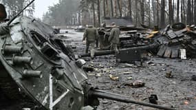 Des militaires ukrainiens marchent entre des chars russes détruits lors de combats à Dmytrivka (ouest de Kiev), le 2 avril 2022 