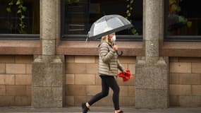 Un femme portant un masque et marchant dans les rues désertes de la ville de Manchester au Royaume-Uni 