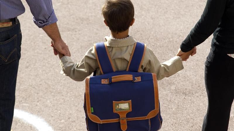 Un enfant tenant la main à des adultes (photo d'illustration)