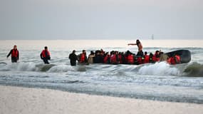 Un passeur (c) debout parmi des migrants à bord d'un bateau pneumatique pour tenter de traverser illégalement la Manche vers la Grande-Bretagne, le 11 juillet 2022 près de Gravlines, dans le Nord